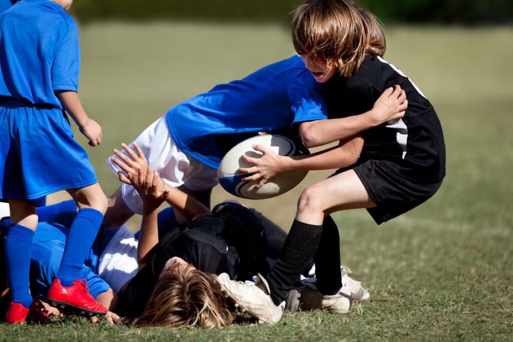 Des enfants en tenue de rugby se passent le ballon sur un terrain d'herbe pendant un entraînement